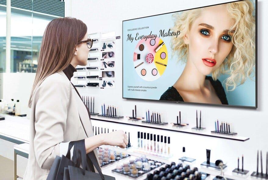 A woman views a retail digital signage display in a cosmetic store