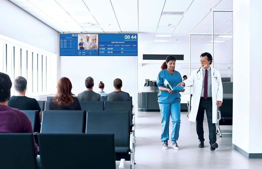 Hospital digital signage displaying scheduling updates to patients in a medical waiting room