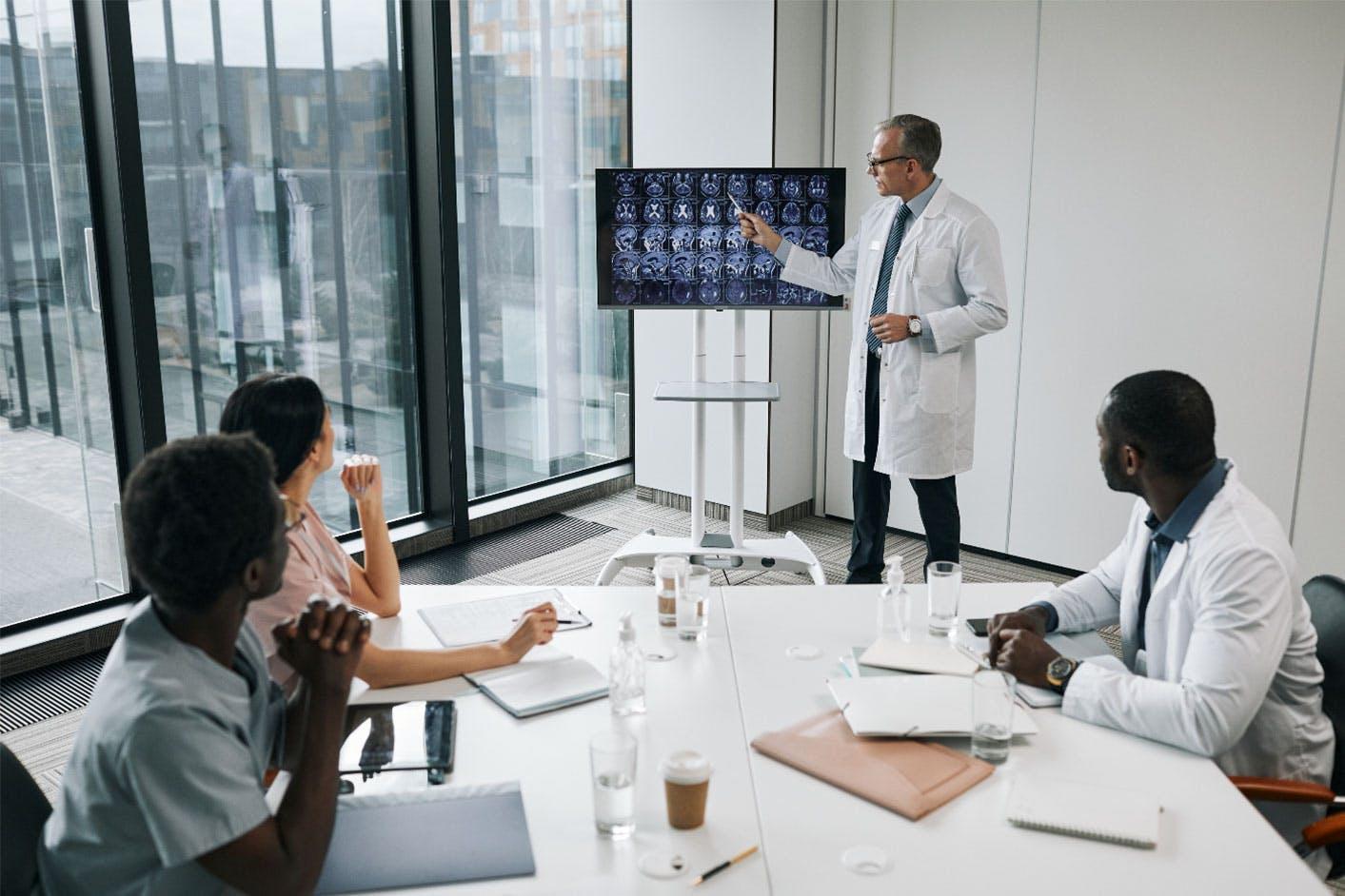 A medical professional uses hospital digital signage to present meeting